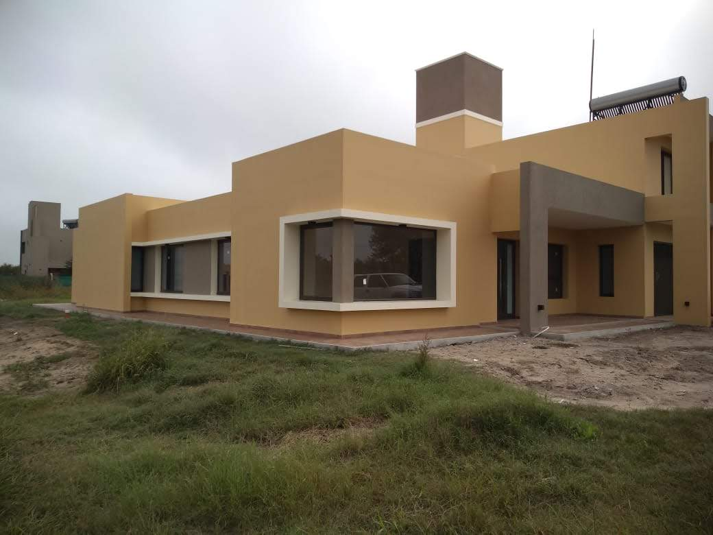 Vivienda con ventana esquinera y aberturas oscuras sobre fachada en tonos cálidos