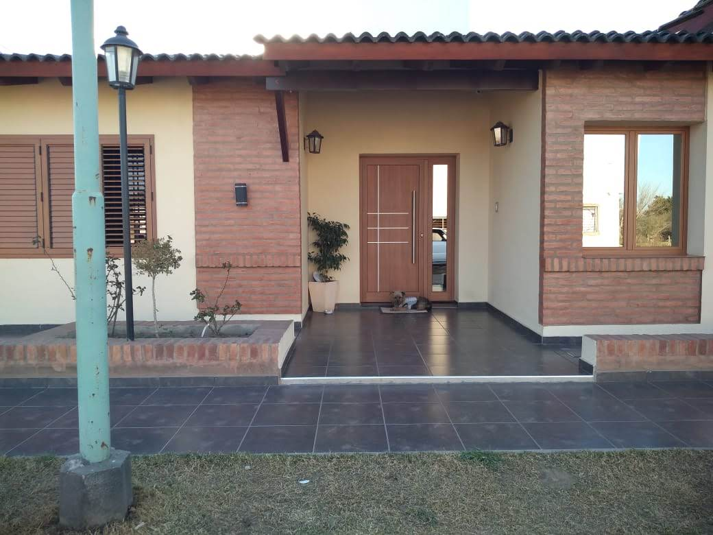 Acceso con puerta, paño lateral, ventanas y postigos en tono madera