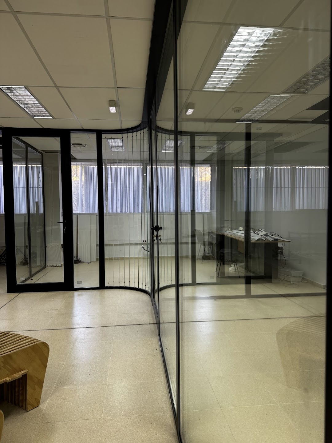 Vista de oficina dividida por puertas y paños de vidrio con perfiles negros