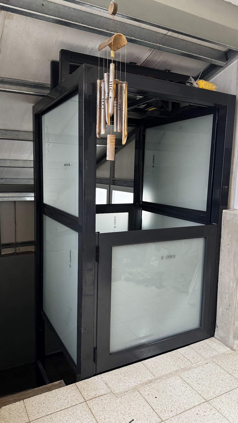 Estructura interior de perfiles negros con paños translúcidos y puerta baja