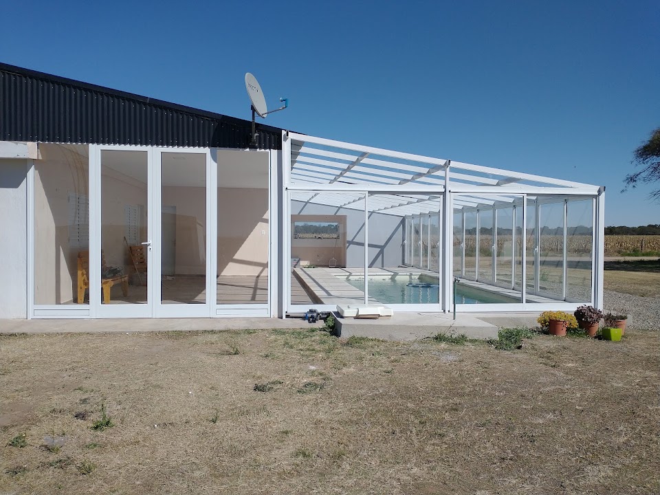 Estructura blanca y paños vidriados alrededor del sector de pileta