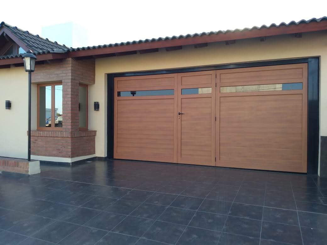 Portón amplio en tono madera con puerta central y vidrios horizontales