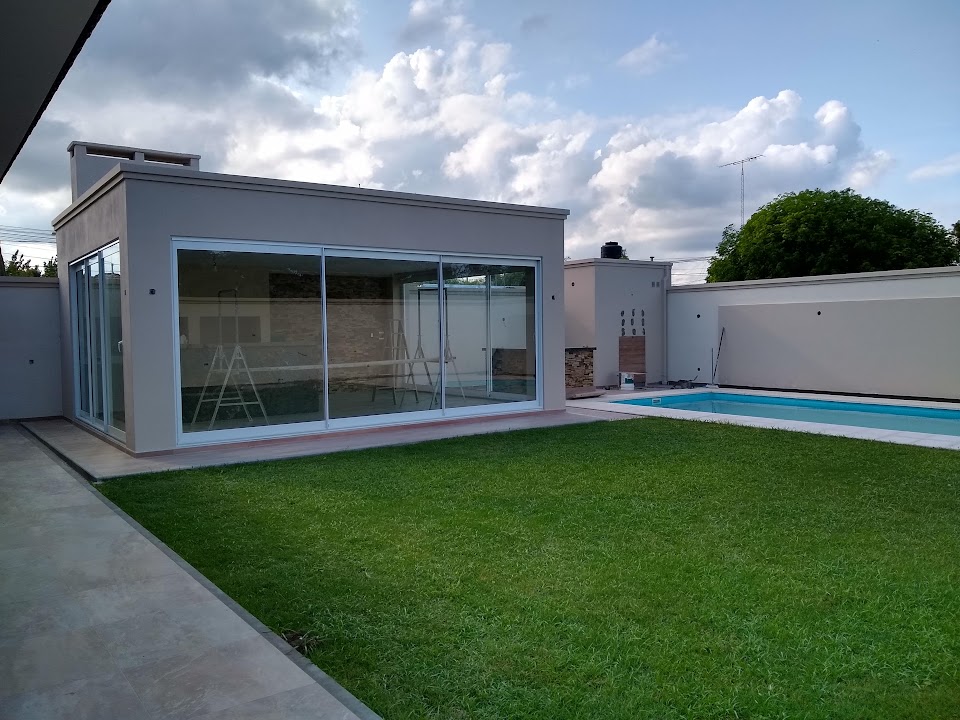 Quincho con cerramiento blanco junto a jardín y pileta
