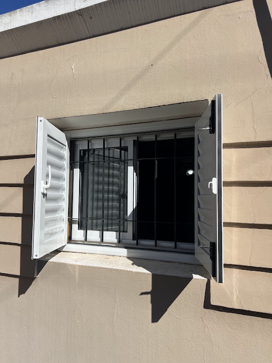 Ventana con postigos blancos abiertos en fachada