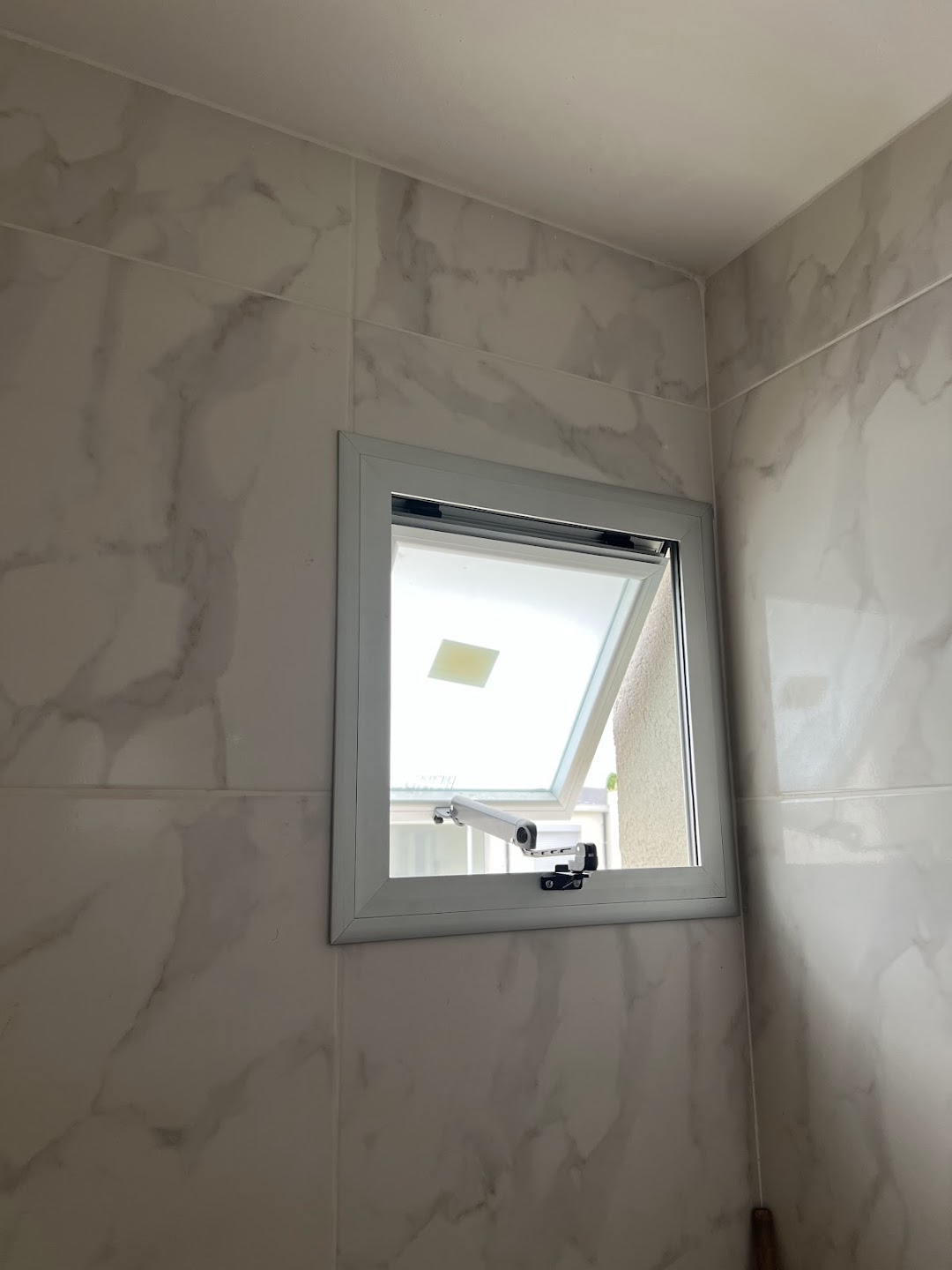 Ventana con apertura hacia el exterior y brazo de accionamiento