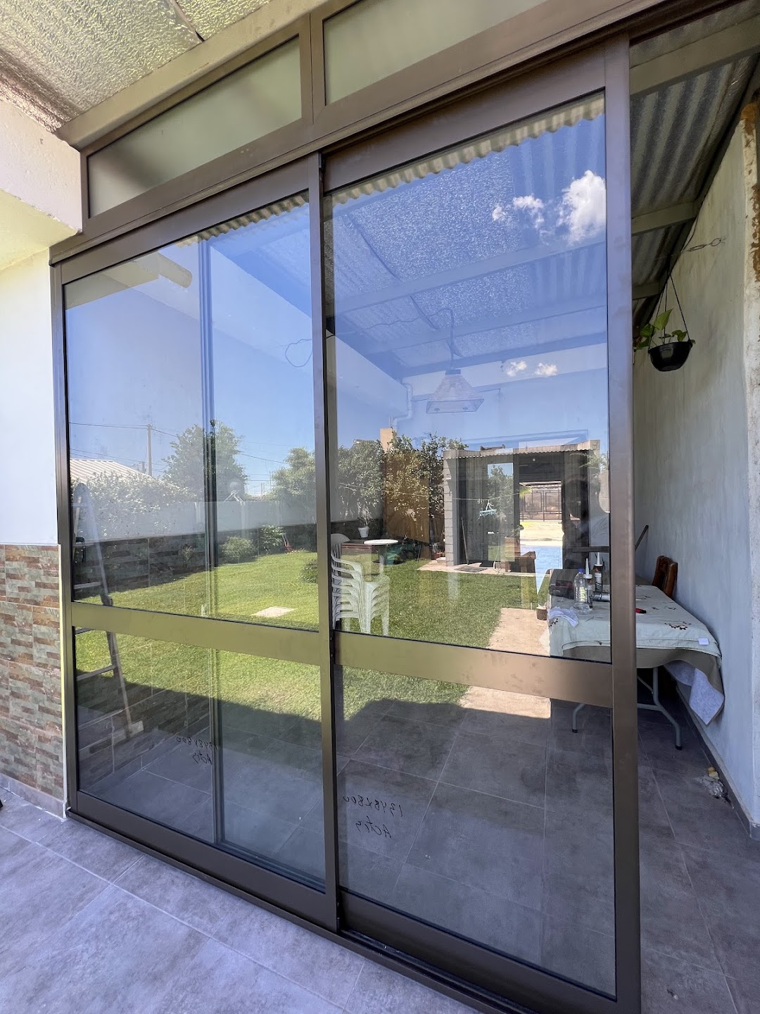 Puertas ventanas corredizas de gran altura con perfiles oscuros y paños vidriados superiores